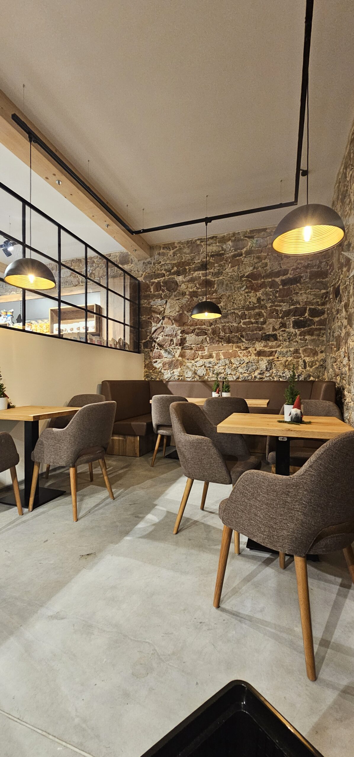 Cafébereich mit Pendelleuchten und beleuchteter Natursteinwand